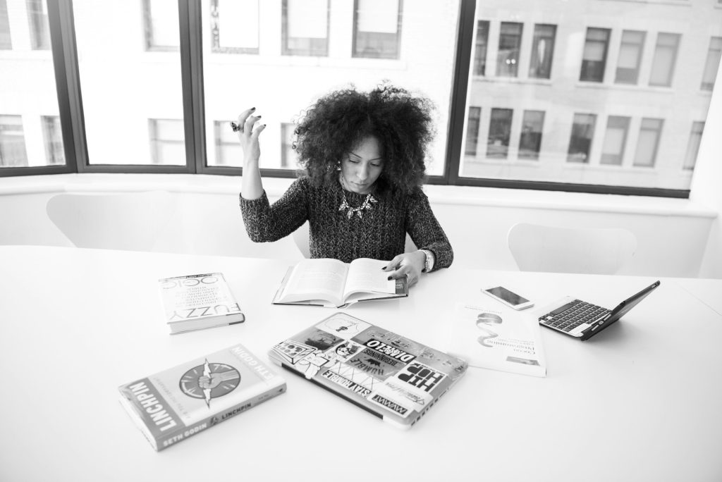 A ghostwriter typing on a laptop surrounded by real estate magazines