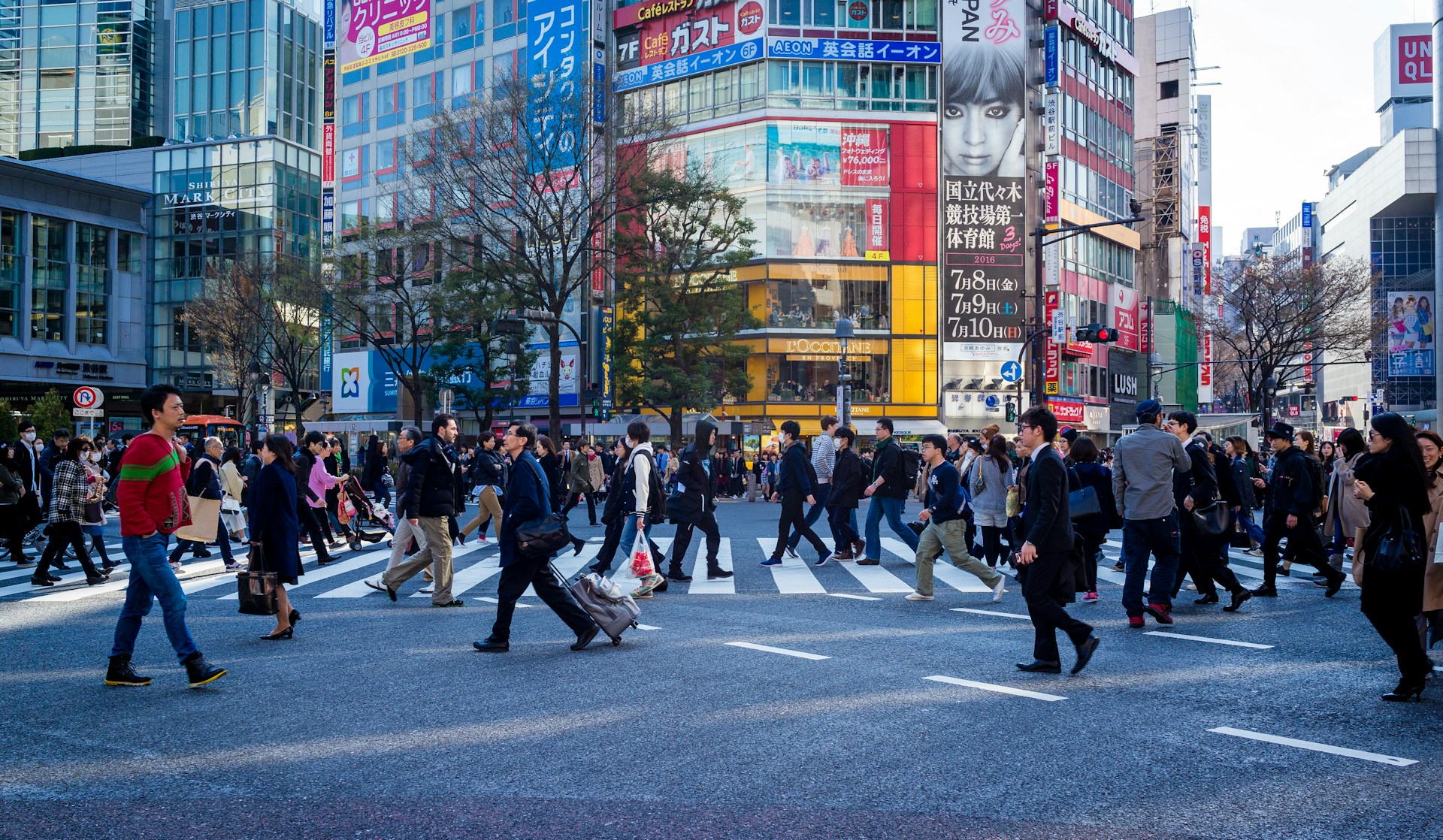 A bustling city street with modern buildings and signs advertising property management services. Busy professionals and potential clients pass by