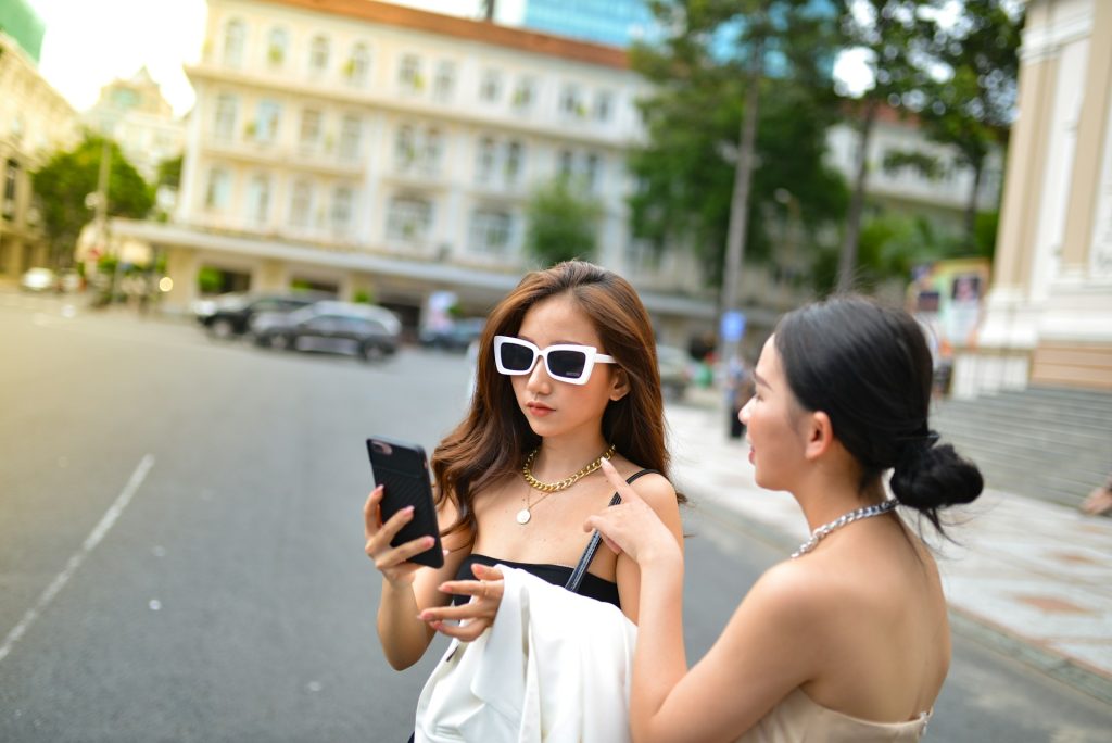 Two girls asking questions about email marketing using their cell phone.