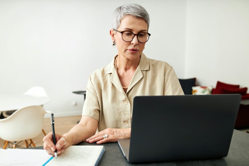 A person at a desk with a computer, surrounded by books and papers, researching and analyzing keywords for SEO web content writing