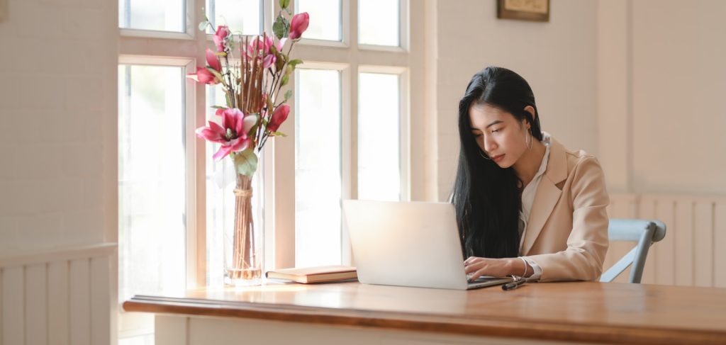 A person writing financial content at a desk surrounded by real estate investment materials and charts