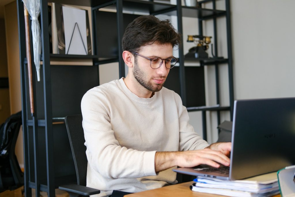 A freelance writer researching landlord insurance, surrounded by open books, a laptop, and notes