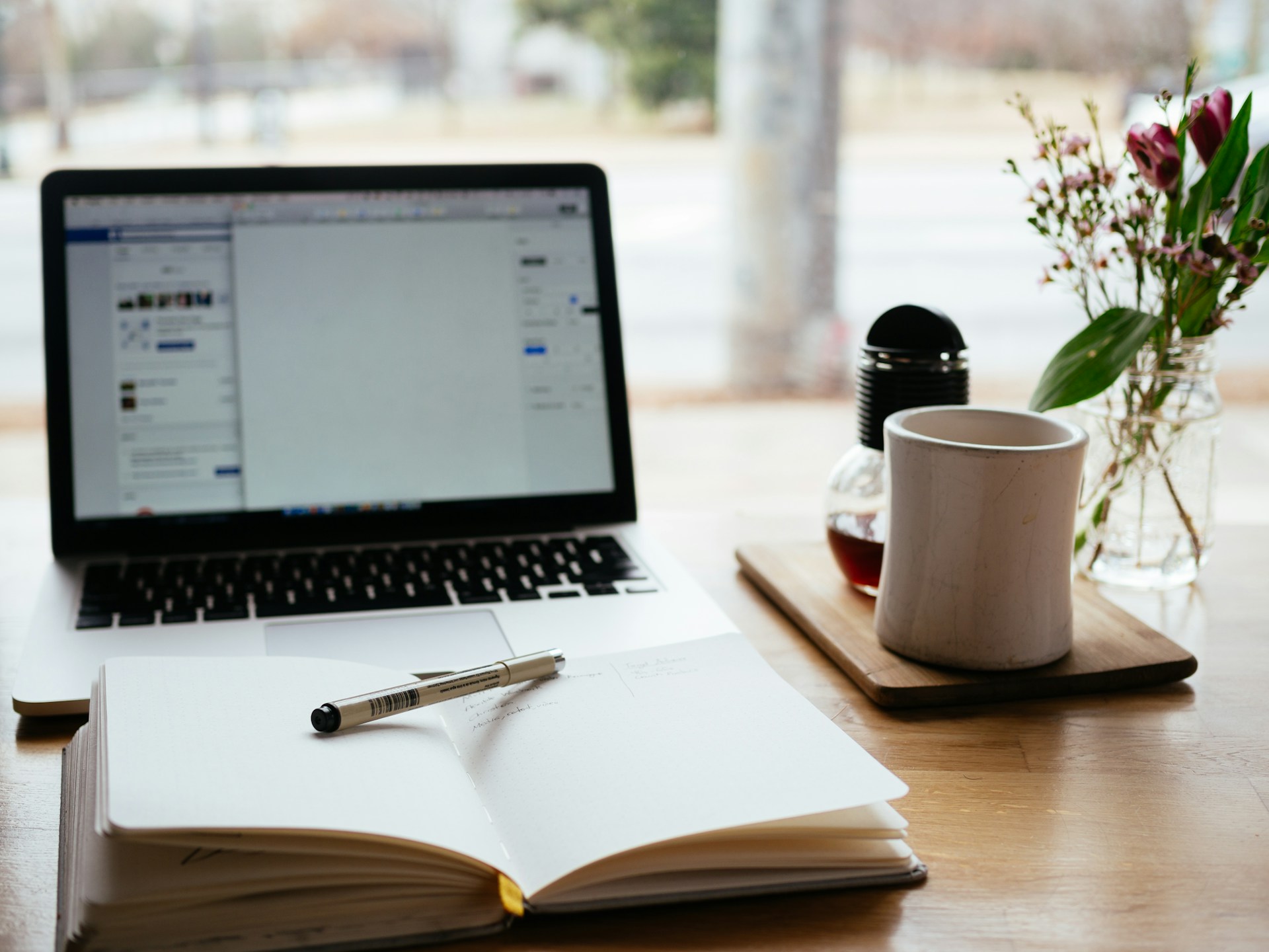 A laptop surrounded by SEO keywords, a cup of coffee, and a notepad