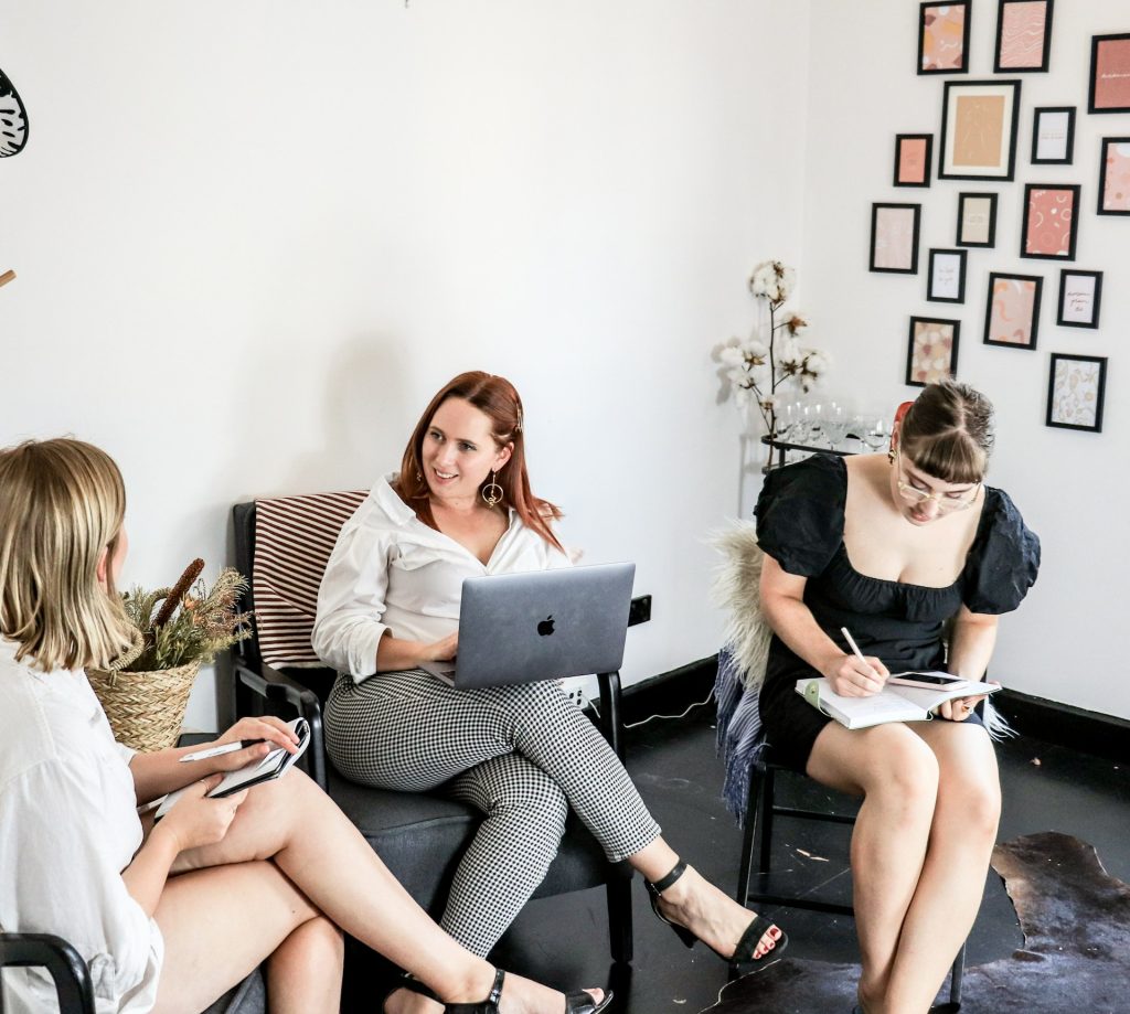 Three female content creators brainstorming about frequently asked questions for real estate blog content ideas.