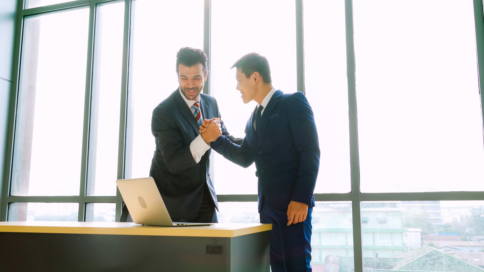 A handshake between a client and a business representative, with both parties smiling and making eye contact