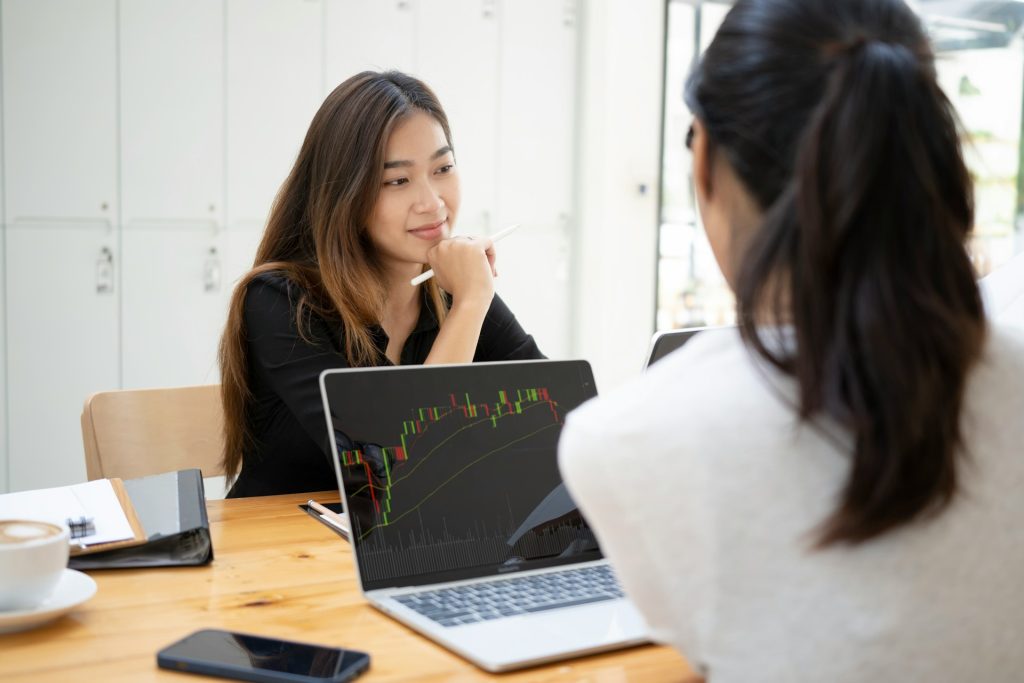 Two women sitting at a desk deciding how to invest in real estate with Bitcoin.