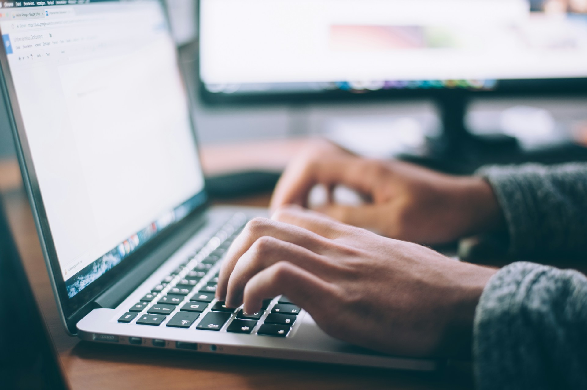 A person typing on a laptop surrounded by financial charts and graphs