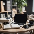 A cluttered desk with a laptop, books, and notes. A cup of coffee sits nearby. The room is quiet and filled with natural light