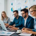 A group of freelance writers working in their office surrounded by market reports and flow charts, brainstorming about real estate investment content and typing on their laptops