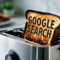 A burnt piece of toast popping out of a toaster with the phrase Google Search on the bread.